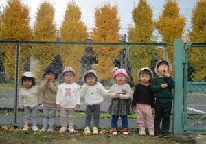綺麗なイチョウの木をバックに写真を撮る１歳児