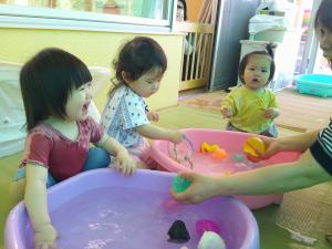 水を触って笑顔になる0歳児