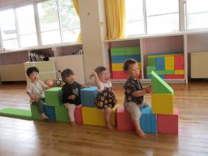 プレールームでカラー積み木で作った電車に乗っている１歳児