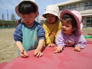 友達が捕まえたダンゴムシに興味津々で見る２歳児