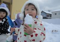 雪をアイスに見立てて食べる真似をする１歳児