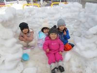 雪の家に入って遊ぶ２歳児