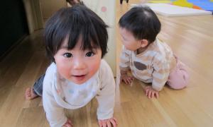 ホールにある大きなトンネルをくぐり笑顔になる1歳児