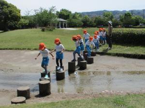 小石に乗って小川を渡る5歳児